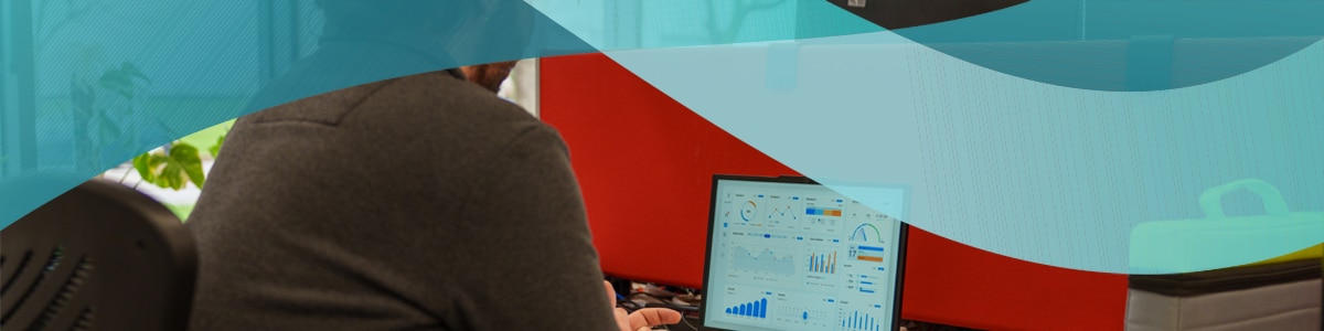 Image of a person working on a computer with his back to the camera and the computer showing fleet management system on its screen